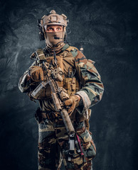 Elite unit, special forces soldier in camouflage uniform posing with assault rifle. Studio photo...