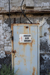 Old rusty door behind a warning sign in an abandoned ruined building