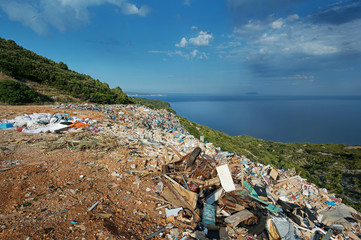 Piles of waste at landfill next to sea. Waste management, ecology, enviromental issues concept