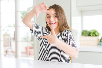 Beautiful young girl kid wearing stripes t-shirt smiling making frame with hands and fingers with happy face. Creativity and photography concept.