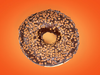Sweet chocolate donut isolated on orange background