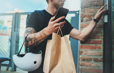 Courier delivery food service at home. Tattooed Man courier delivered the order no name bag with food.