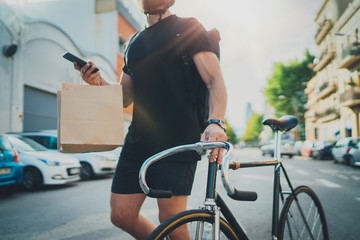 Man courier using a map app on mobile phone to find the delivery address in the city. Anonimous Courier delivery food service at home