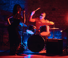 Fototapeta na wymiar Jazz band performance. Young couple of musicians - a drummer and a singer in a nightclub.