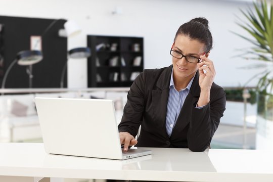 Businesswoman working at office desk with laptop