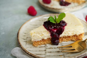 Slice of Hmemade Cheesecake with raspberry blueberry sauce, selective focus