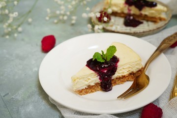 Slice of Hmemade Cheesecake with raspberry blueberry sauce, selective focus