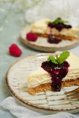 Slice of Hmemade Cheesecake with raspberry blueberry sauce, selective focus