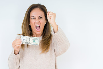 Middle age woman holding 20 dollars bank note over isolated background annoyed and frustrated shouting with anger, crazy and yelling with raised hand, anger concept