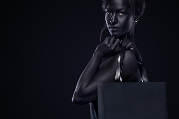 Black friday sale concept. Shopping woman with bodyart and face art holding bag isolated on dark background in holiday.