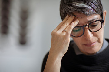 Close-up of stressed businesswoman with head in hand sitting in office