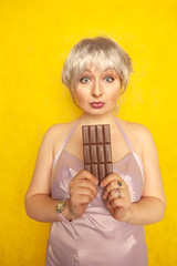 pretty chubby girl with chocolate bar on yellow studio solid background