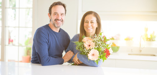 Romantic middle age couple holding flowers in love at home