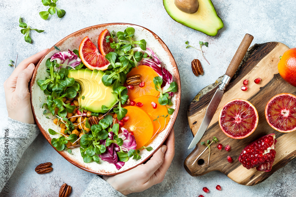 Wall mural girl holding vegan, detox buddha bowl with turmeric roasted chickpeas, greens, avocado, persimmon, b