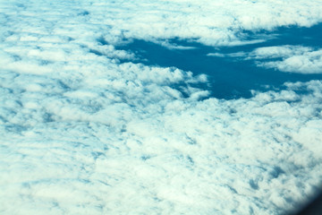 Airplane flying in the blue sky among white clouds