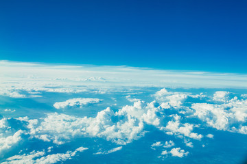 Naklejka na ściany i meble Airplane flying in the blue sky among white clouds