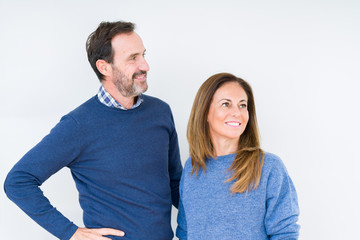 Beautiful middle age couple in love over isolated background looking away to side with smile on face, natural expression. Laughing confident.