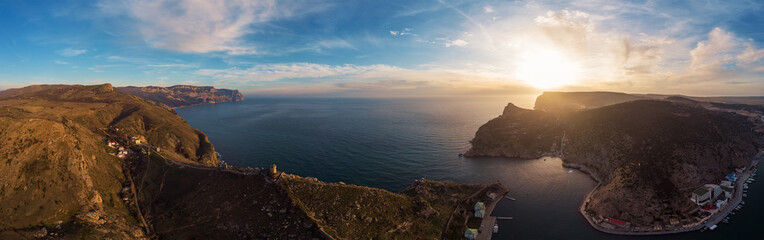 Aerial panorama of Balaklava, Crimea mountain cliffs in enter to bay at sunset. Beautiful nature landscape with sea and coastline