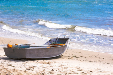 Obraz premium Rescue iron boat with oars, standing on the sandy shore of the sea.