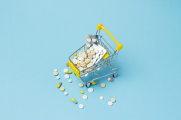 Shopping cart from the supermarket full of pills on a blue background. Purchases of medical preparations, purchase on the Internet. Flat lay, top view.