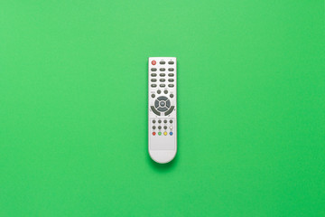 Gray remote control on a green background. The concept of television, movies, TV shows, sports, day...