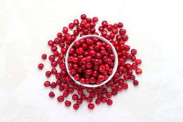 Fresh cherries in a white plate and scattered around on a light stone background. Flat lay, top view