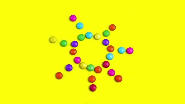 4K video of colorful chocolade smarties. They are changing in the sun and dancing. Then creates other shapes - circle, smile, lines.