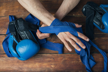 Men's hands during taping before a boxing match against a wooden background. The concept of training for boxing training or fighting. Flat lay, top view