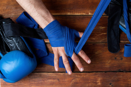 Process of taping male hands before of a boxing match on a wooden background. Boxing gloves lie on the table. Concept of boxing is learning or fighting. Flat lay, top view