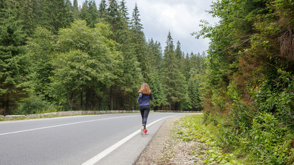 Young slim woman jogging in mountains. Rear view