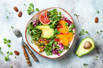 Vegan, detox Buddha bowl with turmeric roasted  chickpeas, greens, avocado, persimmon, blood orange, nuts and pomegranate. Top view, flat lay