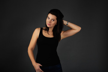 Fototapeta premium Natural beauty concept. Portrait of young attractive smiling woman. Beautiful sporty lady in black top and blue jeans