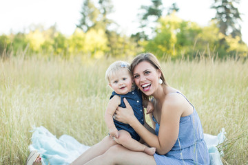 young mother and daughter sitting on blanket smiling