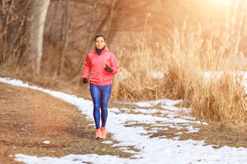Young slim woman jogging in winter park