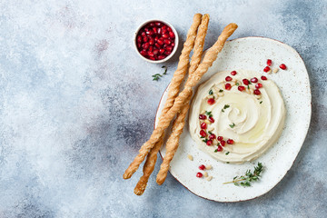 Homemade hummus with pomegranate, thyme, olive oil and pine nuts with grissini bread sticks. Middle...