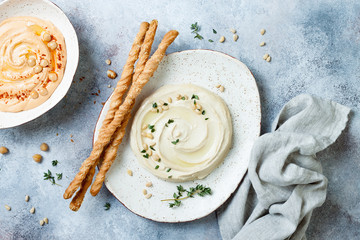 Different homemade hummus bowls. Traditional hummus with thyme, olive oil and pine nuts and roasted...