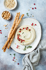 Homemade hummus with pomegranate, thyme, olive oil and pine nuts with grissini bread sticks. Middle...
