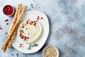 Homemade hummus with pomegranate, thyme, olive oil and pine nuts with grissini bread sticks. Middle Eastern traditional and authentic arab cuisine. Top view, flat lay, overhead