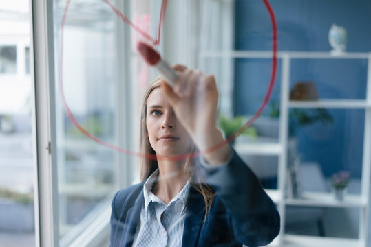Young businesswoman drawing a pie chart on a glass screen