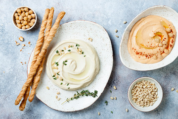 Different homemade hummus bowls. Traditional hummus with thyme, olive oil and pine nuts and roasted pepper or tomato hummus with paprika. Middle Eastern authentic arab cuisine.