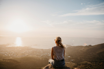 Fototapeta na wymiar South Africa, Cape Town, Kloof Nek, woman sitting on rock at sunset