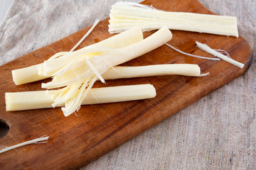 String cheese on rustic wooden board, low angle view. Healthy snack. Closeup.