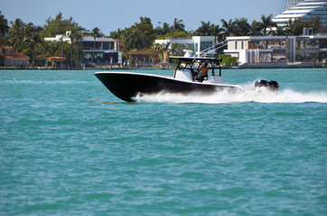 Fototapeta premium Black sports fishing boat with white trim powered by three outboard engines speeding on the Florida Intra-Coastal Waterway
