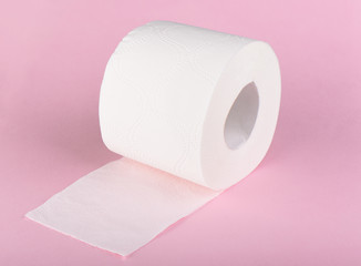 A roll of white toilet paper isolated on a pink background. The paper product used in the sanitary and hygienic purposes.