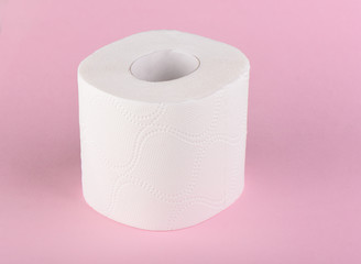 A roll of white toilet paper isolated on a pink background. The paper product used in the sanitary and hygienic purposes.