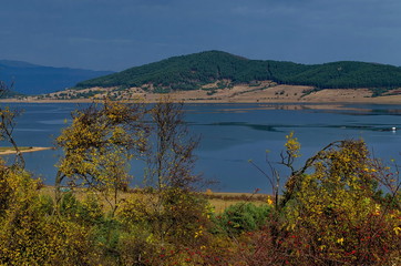 Fototapeta na wymiar Amazing autumn view of glade, hill, shore, forest with deciduous and coniferous trees around Batak dam reservoir, Rhodope mountains, Bulgaria