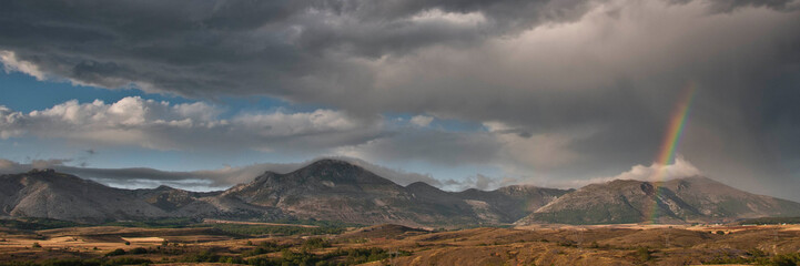 Mountain landscape with a stormy sky and a rainbow