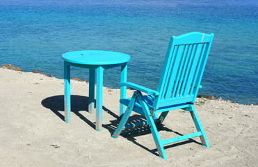 Bright colorful outdoor wooden chairs and table on a sandy beach by the Moorea lagoon in French Polynesia