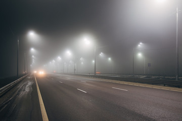 Foggy misty night road illuminated by street lights