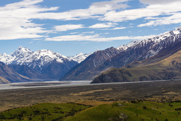 Fototapeta premium Beautiful vast valley with mountains on the horizon, snowy mountain peaks, during sunny with dramatic sky